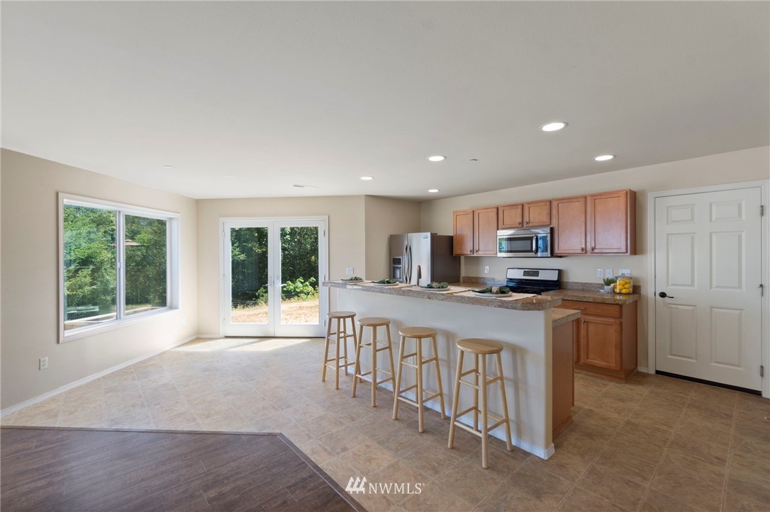 3129 Walker Road DuPont, WA 98327 - Photo 11 of 33 a kitchen with stainless steel appliances kitchen island granite countertop a stove a sink a refrigerator white cabinets and a refrigerator