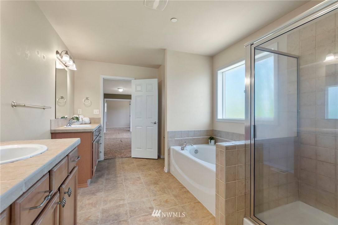 3129 Walker Road DuPont, WA 98327 - Photo 28 of 33 a bathroom with a granite countertop sink a bathtub a mirror and a shower