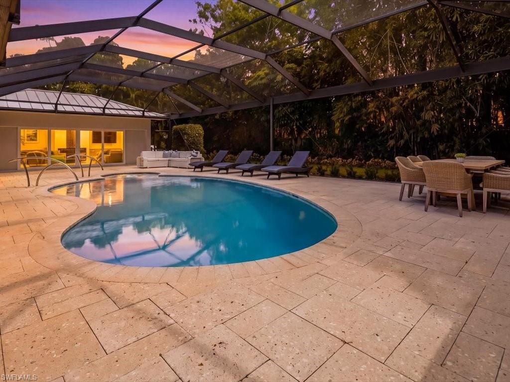 1390 Mandarin Road Naples, FL 34102 - Photo 23 of 50 Screened outdoor living area featuring a freeform pool with integrated steps, neutral-toned paver decking, and extensive mature landscaping