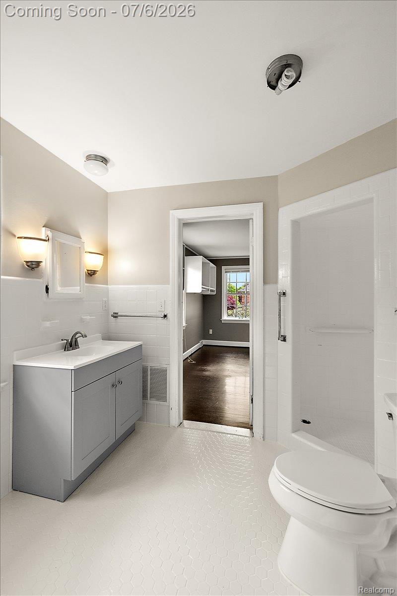 1051 Devonshire Road Grosse Pointe, MI 48230 - Photo 38 of 98 Bathroom featuring hexagonal floor tiling, a gray vanity with an integrated sink, and wall-mounted sconces