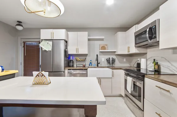 a kitchen with kitchen island granite countertop a sink stainless steel appliances and white cabinets
