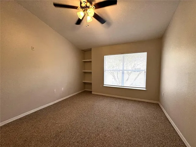 an empty room with a window and a fan