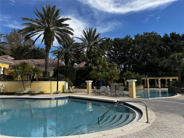 a view of a swimming pool with a lounge chair and palm trees
