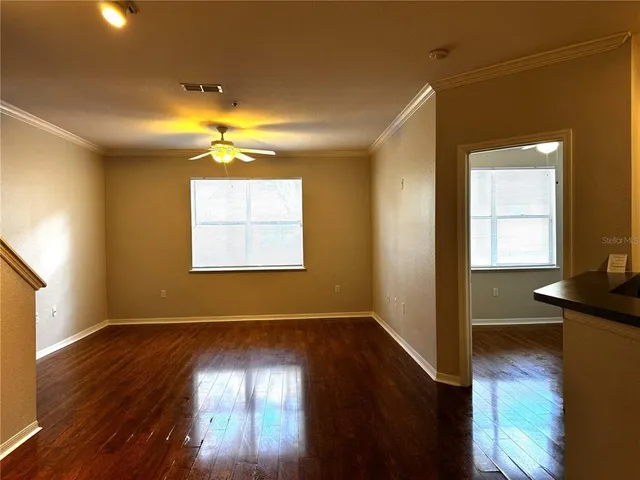 an empty room with wooden floor and windows