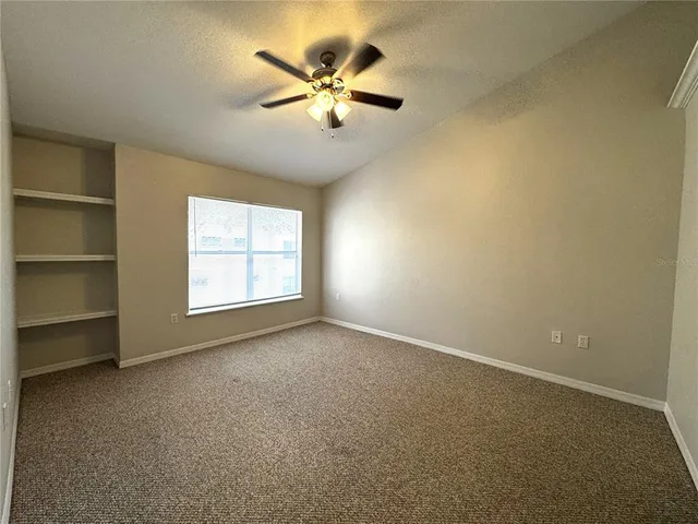 an empty room with a window and a fan