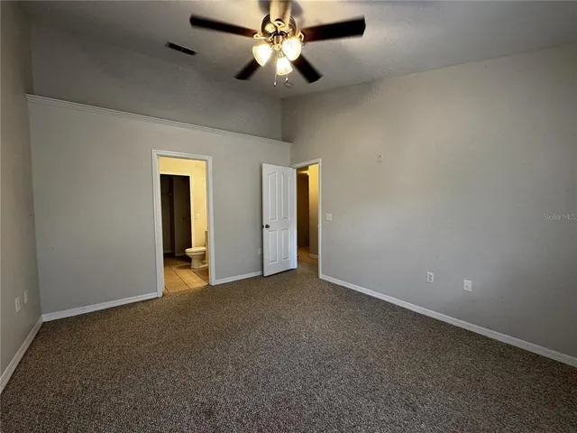 an empty room with closet and a chandelier fan