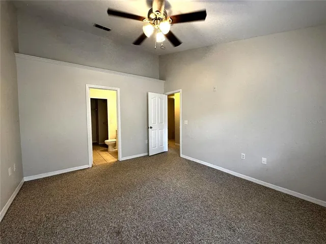 an empty room with closet and a chandelier fan