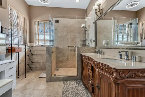 a bathroom with a granite countertop sink a mirror and a shower