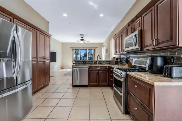 a kitchen with stainless steel appliances granite countertop a stove top oven a sink dishwasher a refrigerator and cabinets with wooden floor