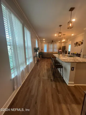 a open kitchen with stainless steel appliances granite countertop a stove top oven a dining table and chairs with wooden floor