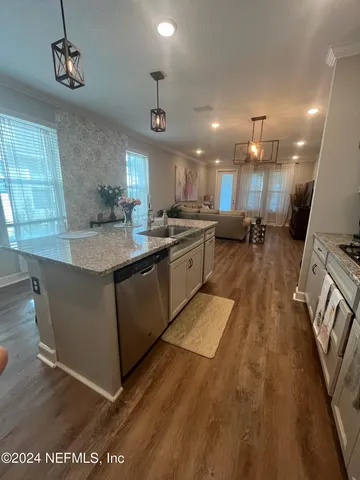 a kitchen with stainless steel appliances granite countertop a sink a stove and a wooden floors