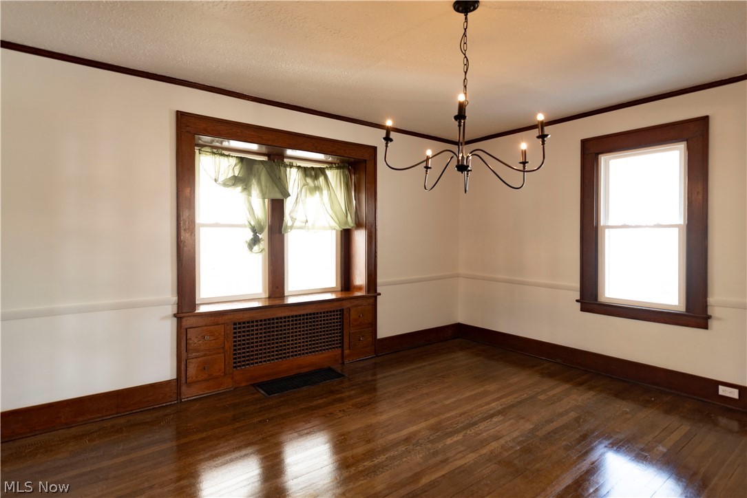 1022 North Howard Street Akron, OH 44310 - Photo 6 of 38 Dining room featuring a chandelier, textured ceiling, wooden built-ins around cold air return and dark hardwood floors