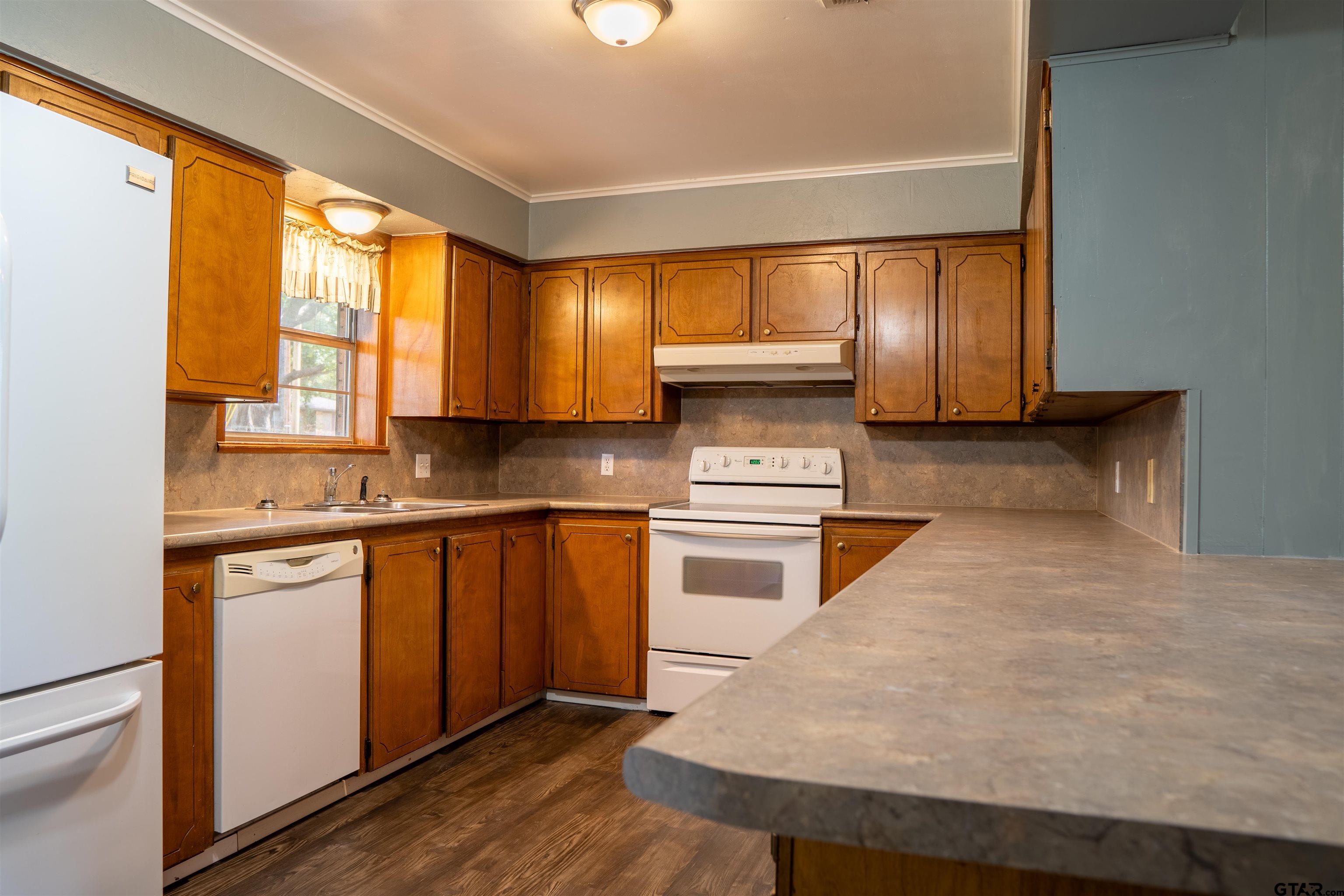 4006 Mark Lane Mount Pleasant, TX 75455 - Photo 12 of 28 a kitchen with stainless steel appliances a stove a sink and white cabinets with wooden floor