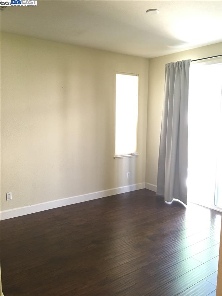 2846 Mint Common Livermore, CA 94551 - Photo 11 of 17 an empty room with wooden floor and windows with curtains