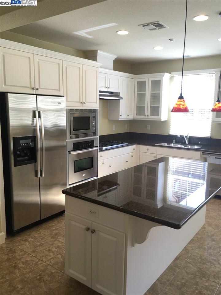 2846 Mint Common Livermore, CA 94551 - Photo 4 of 17 a kitchen with stainless steel appliances kitchen island granite countertop a refrigerator a stove and a sink with wooden floor