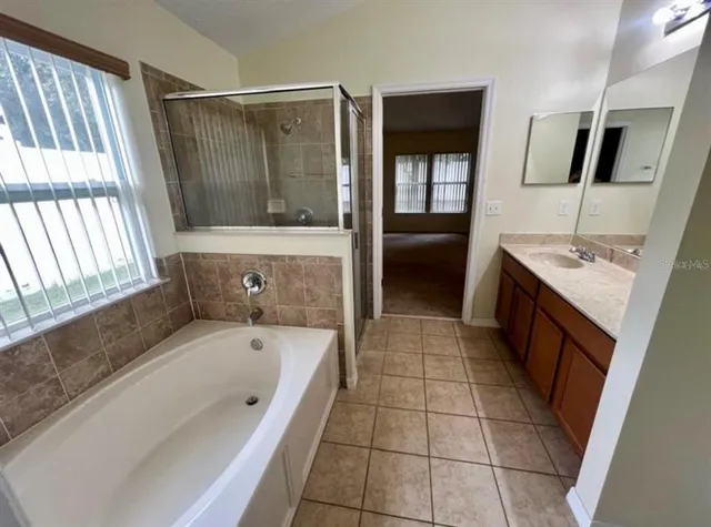 a bathroom with a tub a double vanity sink a window and mirror