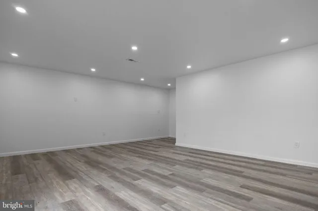 an empty room with wooden floor and natural light