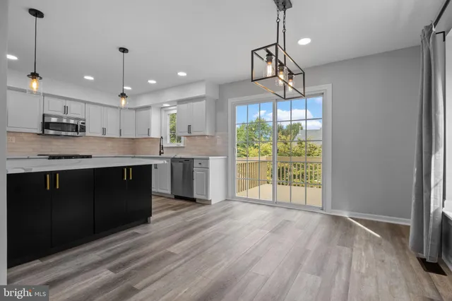 a kitchen with stainless steel appliances granite countertop a refrigerator a sink dishwasher a stove and white cabinets with wooden floor