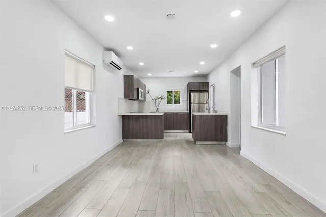 a living room with stainless steel appliances kitchen island hard wood floors and fireplace