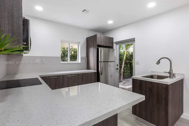 a kitchen with a sink a refrigerator and a stove top oven
