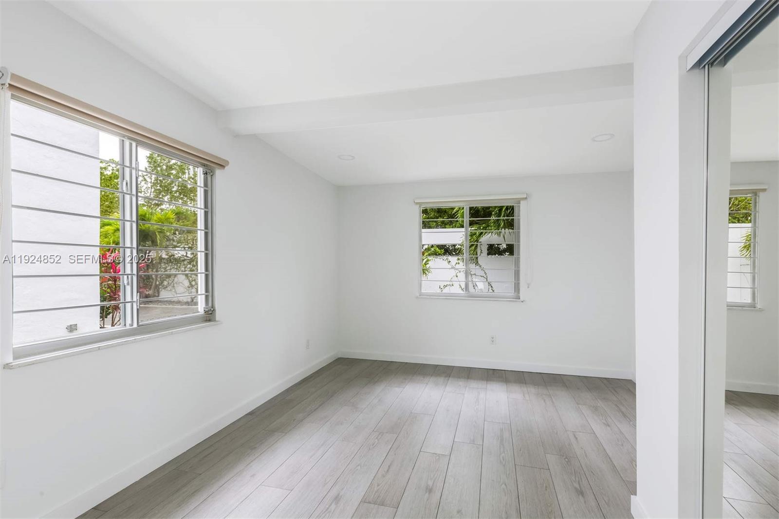 623 Northeast 61st Street, Unit 5 Miami, FL 33137 - Photo 10 of 12 an empty room with wooden floor and windows