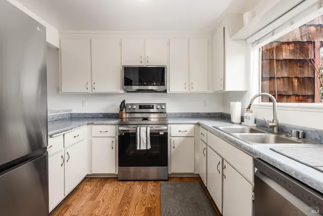 a kitchen with stainless steel appliances granite countertop a stove and white cabinets