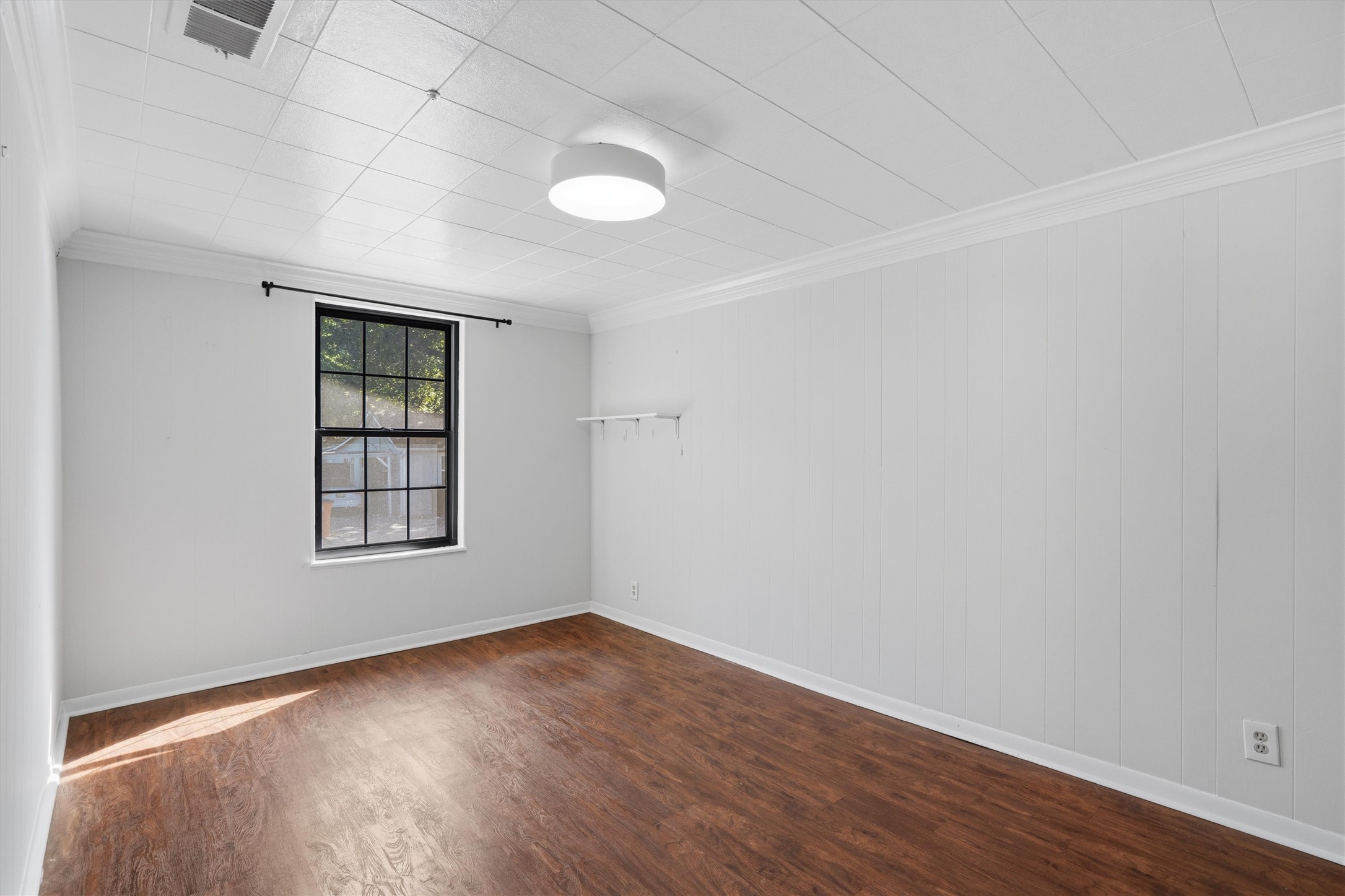 2204 Santa Rita Street Austin, TX 78702 - Photo 11 of 23 Rich wood-look flooring and a classic multi-pane window anchor this versatile interior room.