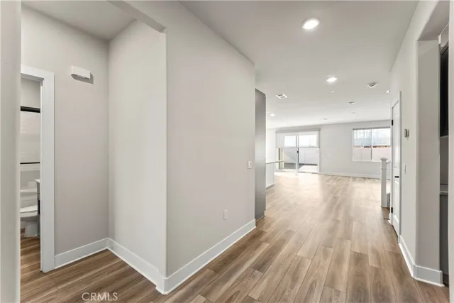 a view of a hallway with wooden floor and a bathroom