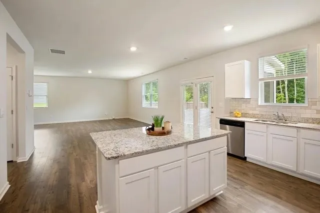 a kitchen with stainless steel appliances granite countertop wooden cabinets a sink a window and a counter space