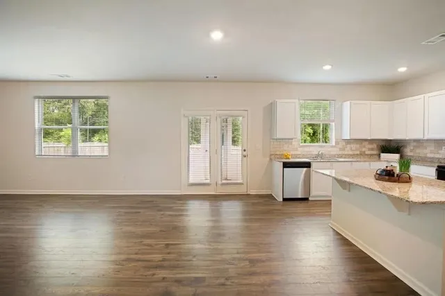 a kitchen with granite countertop wooden floors a stove and white stainless steel appliances