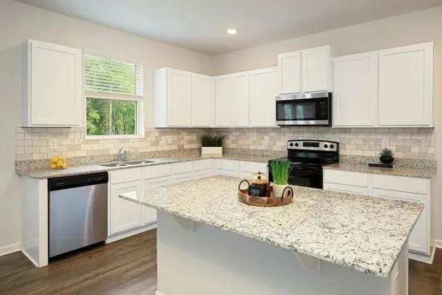 a kitchen with kitchen island granite countertop a sink counter top space appliances and cabinets