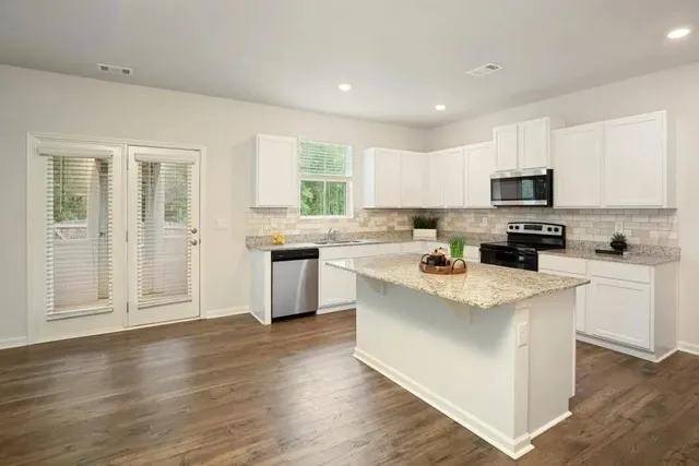 a kitchen with stainless steel appliances white cabinets a sink and a stove