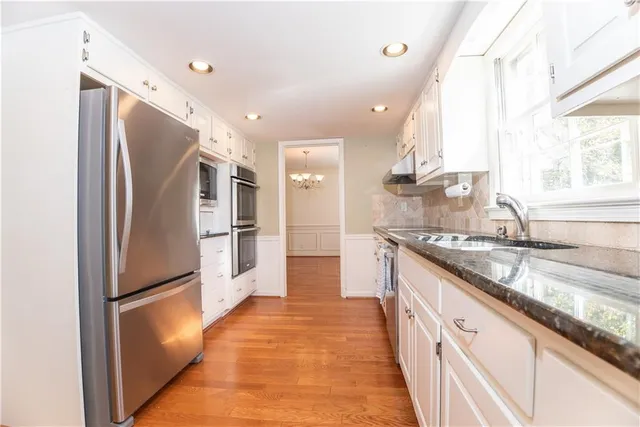 a kitchen with granite countertop white cabinets dining table and chairs