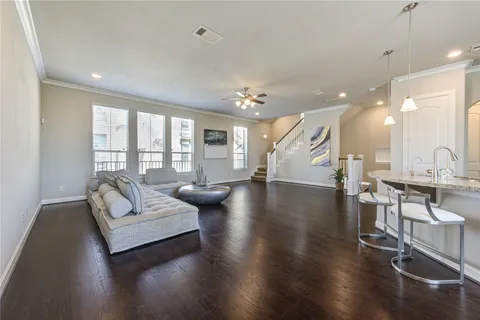 a living room with couches and kitchen view with wooden floor