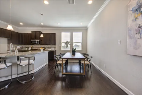 a kitchen with stainless steel appliances kitchen island granite countertop a stove a sink a refrigerator and a dining table with wooden floor