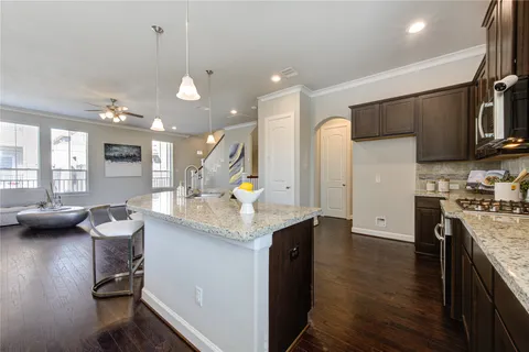 a kitchen with granite countertop a stove a sink and a refrigerator