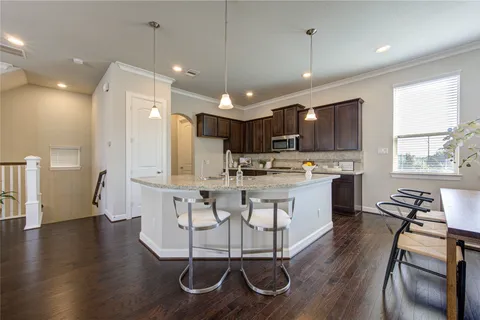 a kitchen with stainless steel appliances kitchen island granite countertop a stove a sink a refrigerator and white cabinets with wooden floor