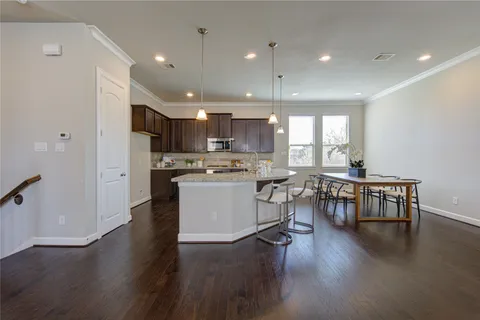 a kitchen with a dining table chairs wooden floor appliances and cabinets