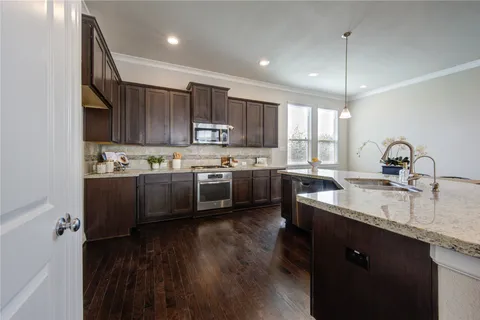 a kitchen with kitchen island granite countertop wooden floors a sink and cabinets