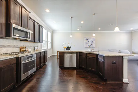 a large kitchen with stainless steel appliances granite countertop a stove a sink dishwasher and a microwave oven with wooden floor