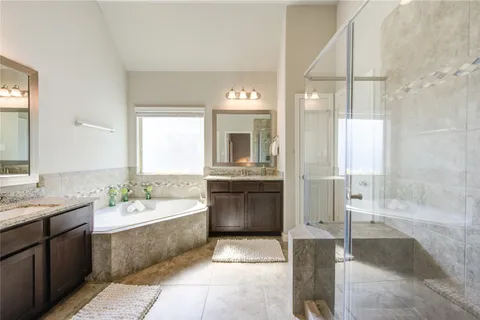 a bathroom with a double vanity sink mirror and bathtub
