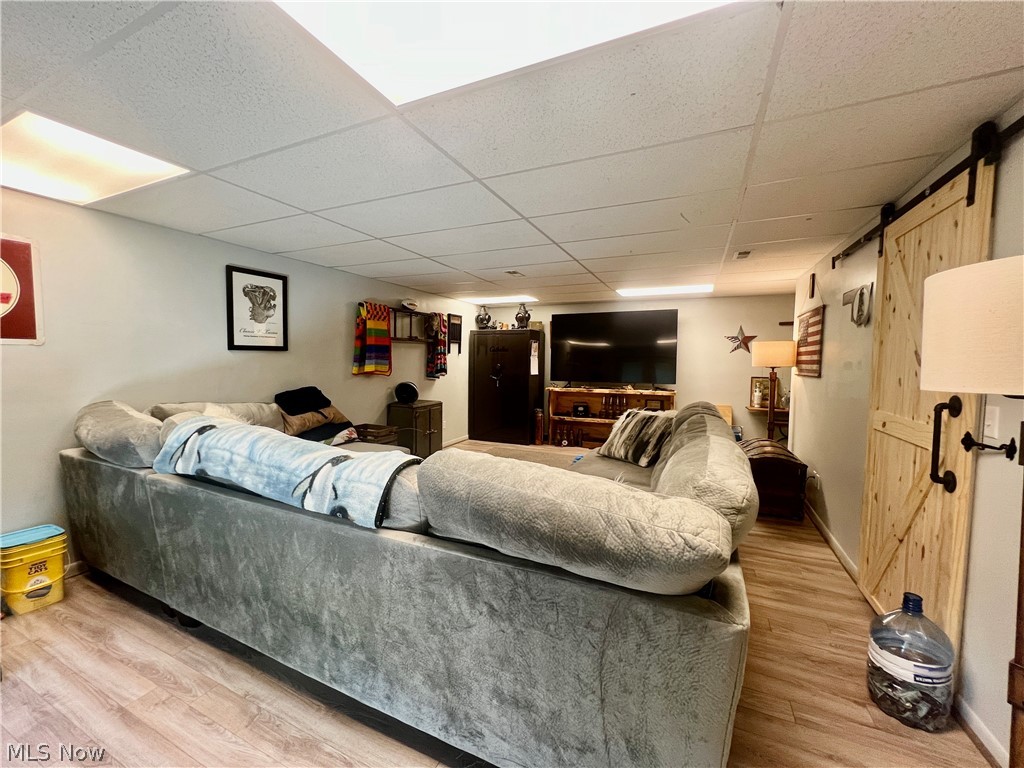 39589 National Road Bethesda, OH 43719 - Photo 20 of 35 Living room featuring a barn door, wood-type flooring, and a drop ceiling