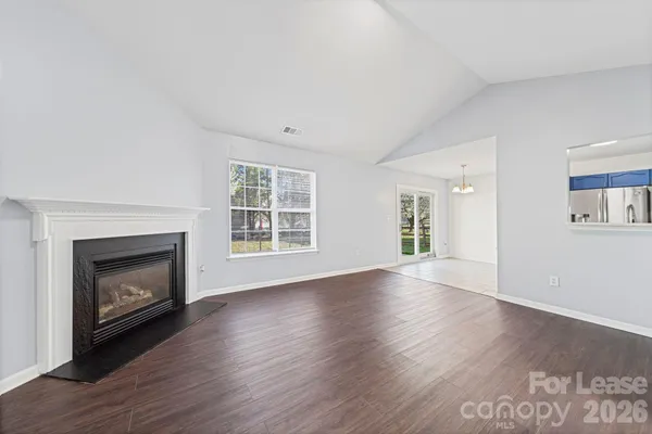 an empty room with wooden floor fireplace and windows