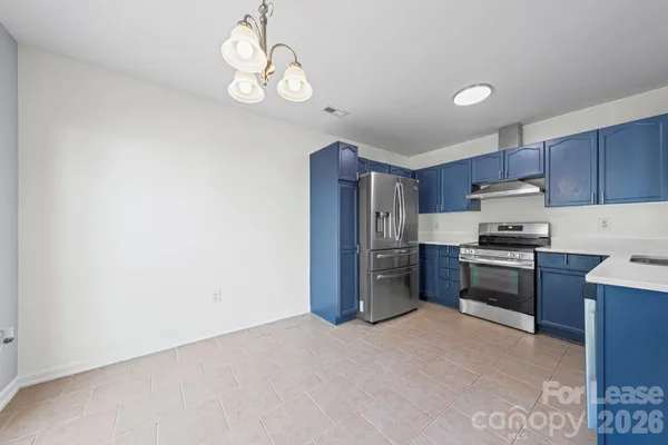 a kitchen with granite countertop a refrigerator stove top oven and sink