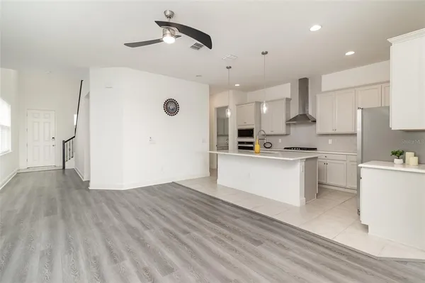 a view of an empty room with wooden floor and a ceiling fan