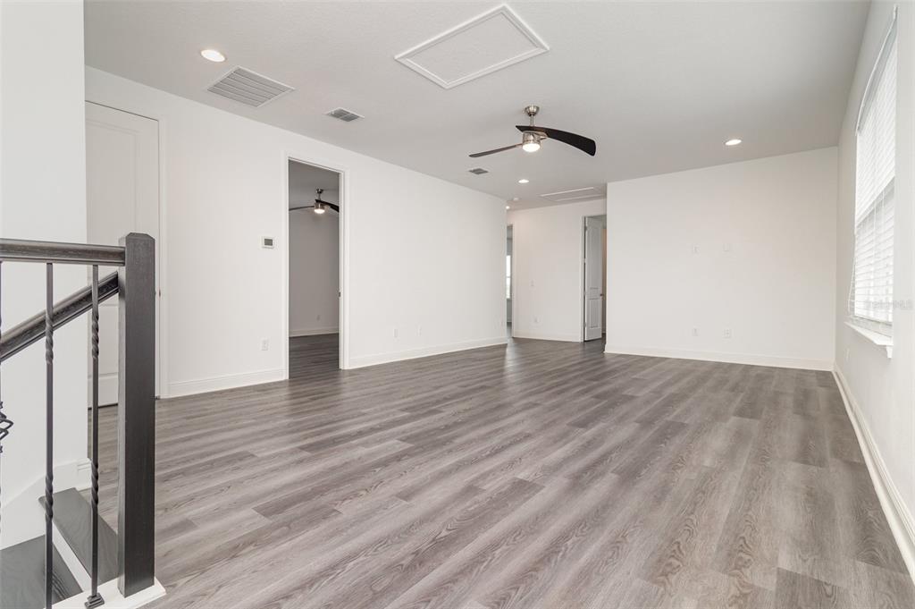 15701 Vetta Drive Montverde, FL 34756 - Photo 31 of 68 a view of an empty room with wooden floor and a ceiling fan