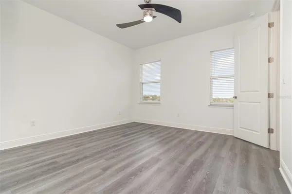 a view of an empty room with wooden floor and closet