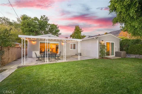 a patio with table and chairs and potted plants