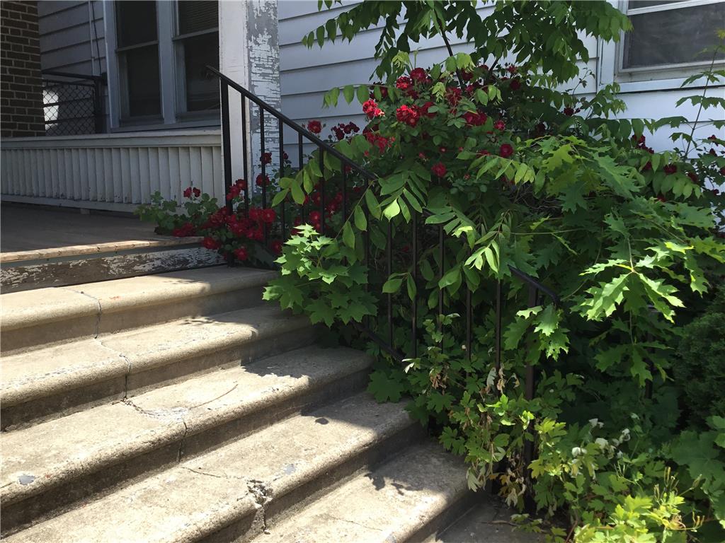 1105 Main Street Slatington, PA 18080 - Photo 31 of 31 Concrete steps lead to a welcoming porch, framed by vibrant green foliage and scarlet blooms.