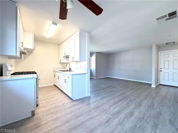 a kitchen with stainless steel appliances granite countertop a sink cabinets and wooden floor